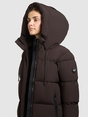 Model trägt dunkelbraune Steppjacke mit großer Kapuze, Reißverschluss und schwarzen Kordelzügen.