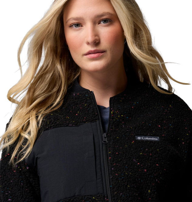 Schwarze Columbia-Fleecejacke mit bunten Sprenkeln, Frontreißverschluss und dunkler Brusttasche am Modell.