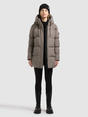 Model trägt eine taupefarbene Steppjacke mit Kapuze, schwarzer Mütze und schwarzen Stiefeln.
