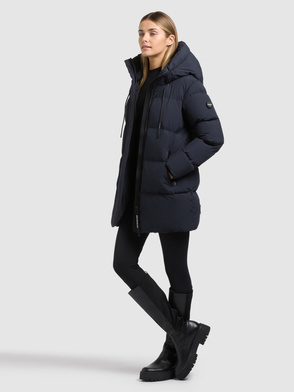 Model trägt einen dunkelblauen, gesteppten Parka mit Kapuze und Stehkragen.