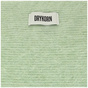 Detailaufnahme eines hellgrünen, flauschigen Strickstoffs mit weißem Drykorn-Label.