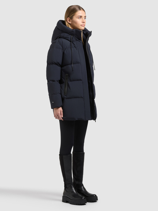 Model trägt einen dunkelblauen, wattierten Parka mit hohem Kragen und Reißverschlusstaschen.