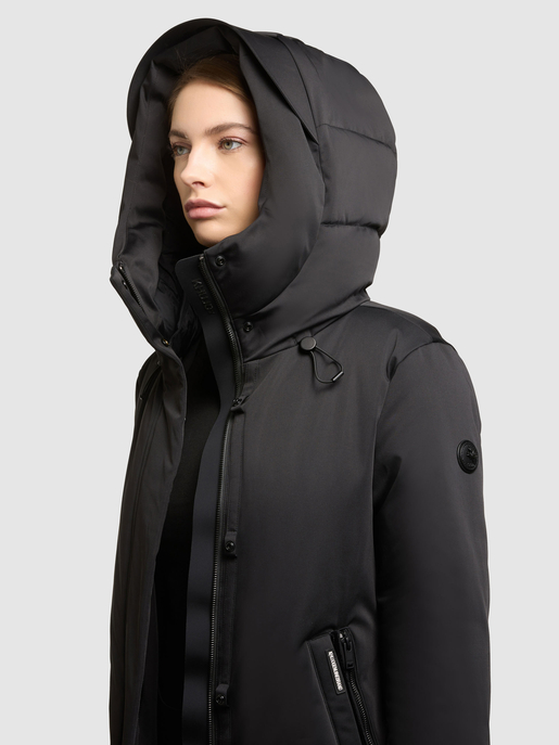 Model trägt schwarzen Winterparka mit hochgezogener Kapuze, Reißverschluss und Seitentasche.