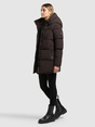 Model trägt dunkelbraunen, wattierten Parka mit Kapuze und Reißverschlusstaschen.