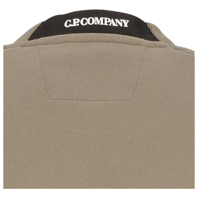 Detailansicht eines beigefarbenen Sweatshirts mit schwarzem Nackenlabel von C.P. Company.