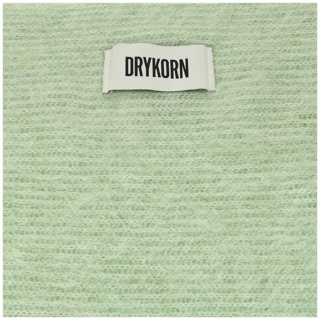 Detailaufnahme eines hellgrünen, flauschigen Strickstoffs mit weißem Drykorn-Label.