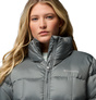 Graue Columbia Steppjacke mit hohem Kragen, Frontreißverschluss und Logo auf der Brust, am Model.