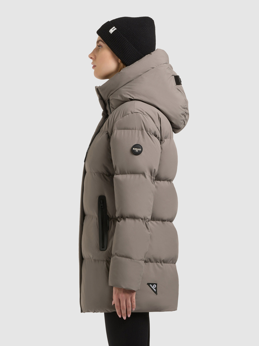 Model trägt einen taupefarbenen Steppmantel mit großer Kapuze in Seitenansicht.